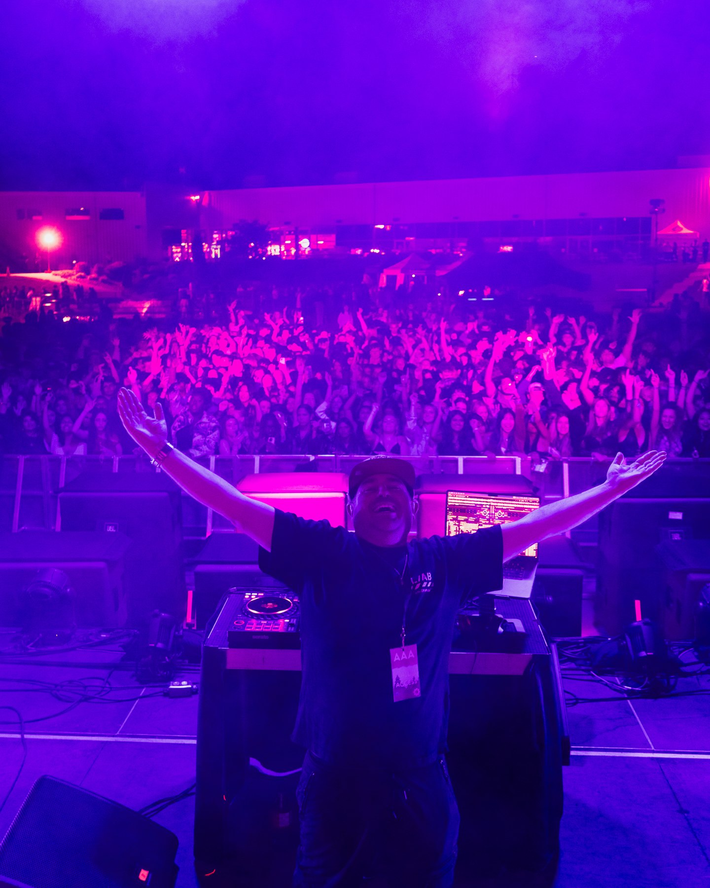 View from the DJ booth over a crowd bathed in purple concert lights