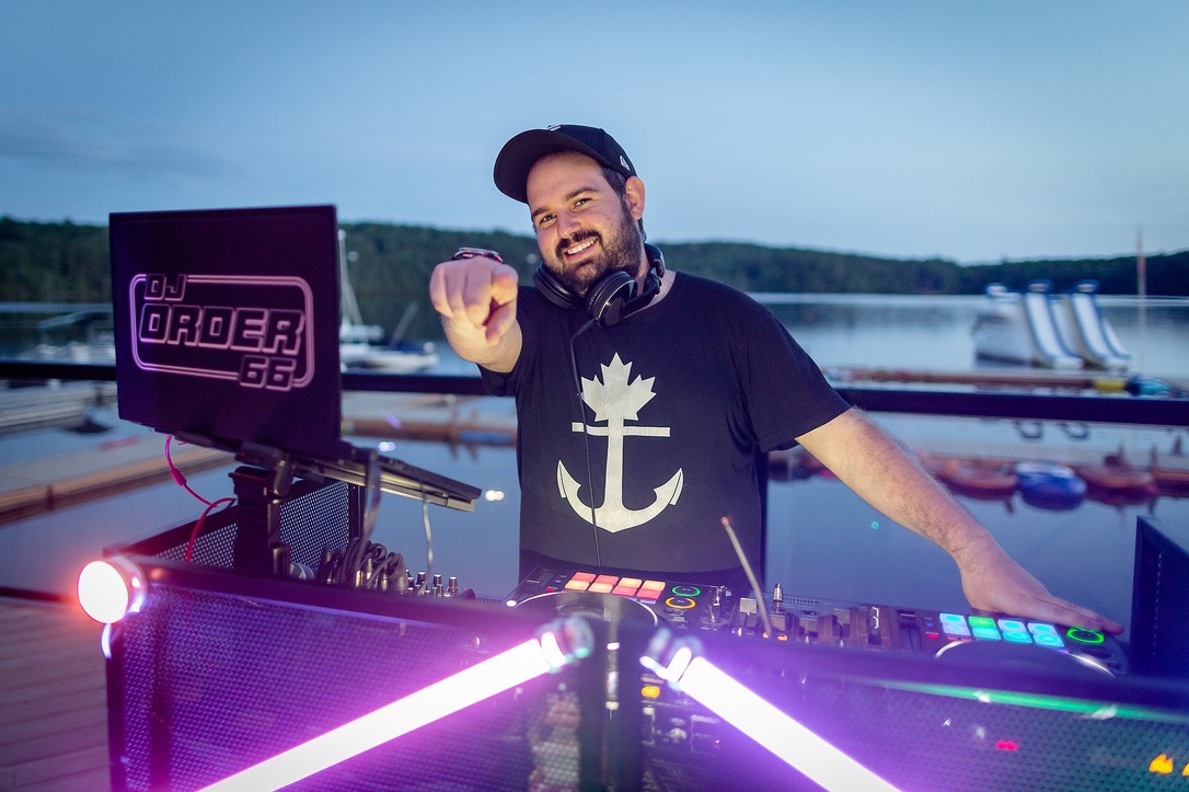 Dylan DJing beside the waterfront with colourful booth lighting