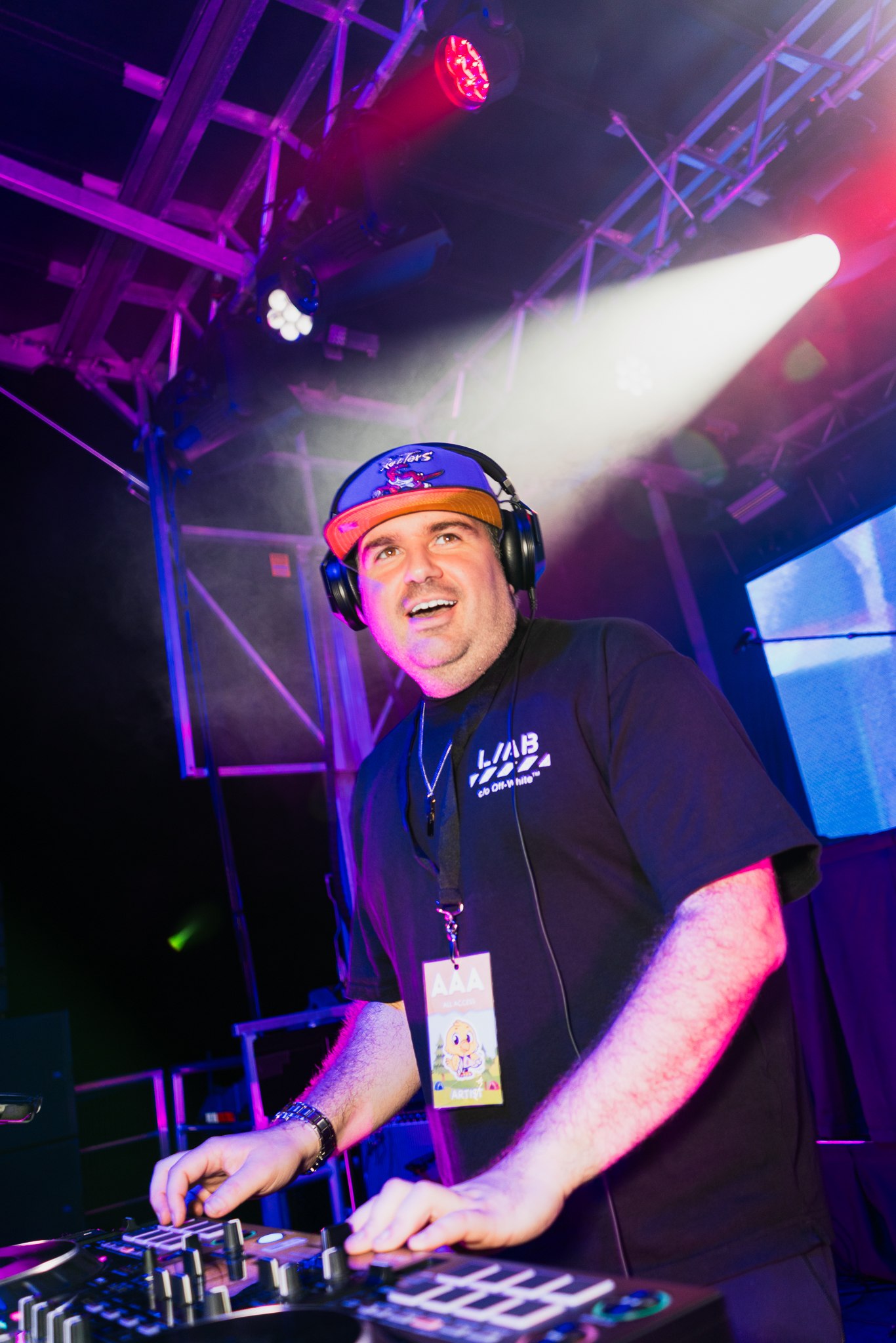 Dylan smiling while mixing at the decks under colourful stage lights